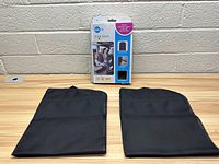 Two black fabric kick mats laid flat on a table showing size and shape, made to protect car upholstery.