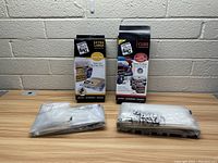 Two boxes of Space Bags vacuum storage bags with plastic bags packed in front of a brick wall on a wooden table.