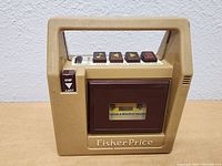 Front view of vintage beige Fisher-Price cassette player with cassette door and stop/eject switch