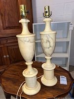 Pair of alabaster table lamps on wood table showing full height and design.