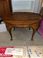 Front view of the wood coffee table showing scalloped edges, wood grain, and cabriole legs.