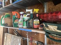 Wide shot of gardening supplies on wooden shelf with basket, various pesticide bottles, folded fabric bin, and rolled plastic fencing