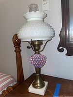 Front view of the vintage lamp showing the white milk glass hobnail shade, brass base, and purple hobnail glass midsection