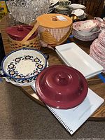 View of full lot showing Longaberger covered pot, bread basket, pie plate, baking dishes, and surrounding items