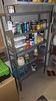 Front angled view of the metal shelf showing all five shelves and various paint cans on the shelves (not included).
