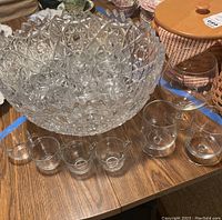 Large cut glass punch bowl and smaller clear punch glasses on wooden table