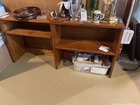 Photo of wooden shelf unit showing left side with door open and right side open shelf area, items on and around shelf not included in sale