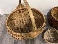 Medium-sized antique wicker basket with wooden handle showing star pattern on base and rounded form.