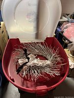 Photo of white Christmas wreath inside red Rubbermaid storage container with lid open
