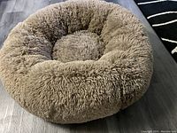 Top-down view of a round beige dog bed showing plush, shaggy, super fluffy fabric and round shape.