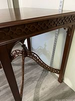 Side view showing carved motifs on apron and cross braces with square legs