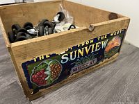 Wooden Sunview apple box containing the lot of casters, hooks, and knobs with visible colorful vintage graphic label on the side.