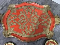 Top-down view of vintage Italian orange decorative tray with gold ornate detailing and handle, showing overall design and condition.