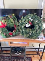 Both Christmas wreaths displayed side by side on a table showing their overall size and decorations.
