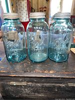 Front view of three blue glass Ball Perfect Mason jars with zinc lids, showing embossed text on each.