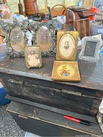 Lot includes six antique picture frames and one oil painting displayed on a wooden surface with vintage items in background.