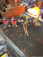 All six painted cast iron winter figures arranged on a rustic wooden surface showing overall set and size.