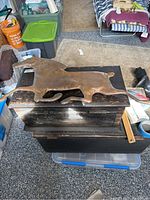 Top view photo showing full horse figure with outstretched legs lying on a wooden surface with surrounding storage containers.