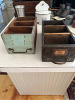Top front view showing both antique painted wood cubby boxes with compartments and metal handles.