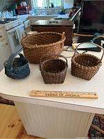 All four splint baskets shown together on a kitchen countertop with ruler for scale.