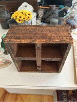 Front view showing four cubby holes and embossed/stenciled advertising on top and front edges.