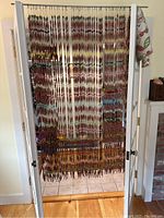 Front view of the colorful beaded curtain hanging in a door frame showing the full length and width with multicolored beads arranged in 55 strands.