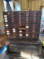 Front view of the 60-drawer wooden watch parts storage box showing all drawers and one open drawer in the center right area.