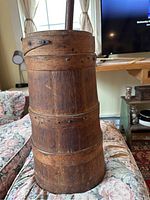 Full view of primitive butter churn body showing finger lap banding, rose head nails and wooden pegs with wooden dasher inserted.