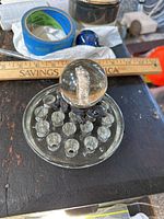Top angled view of a clear sulfide marble paperweight with a standing bear figure inside, sitting on a flat glass base with bubble details, ruler for scale at about 2 inches.
