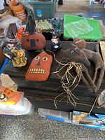 Five primitive Halloween decorations arranged on a black crate including three fabric pieces and two small painted figurines.
