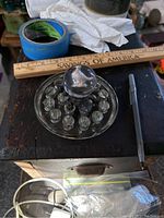 Large sulfide marble on glass holder, blue painter's tape, pen, and ruler for scale in the background.