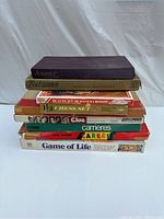 Seven board games stacked including Scrabble, Risk, Chess Set, Clue, Careers, and Game of Life in original boxes showing wear.