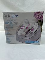Front view of the boxed Conair Complete Facial Care System showing the three devices in a charging base with purple button accents