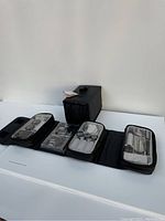 Two black cosmetic travel bags unfolded showing multiple empty cosmetic containers inside.