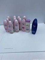 Photo shows a group of multiple sealed bottles of shampoo and conditioner including mostly Dove Advanced Colour Therapy products and one Pantene bottle.