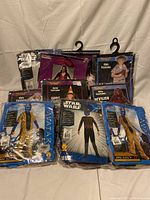 Photo showing several sealed children's Halloween costumes including Star Wars, Avatar, and devilish themes.