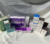 Full view of the lot showing various boxed Avon Anew skincare products including lotions, eye lift creams, body wash and others arranged on a white cloth background.