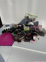 Wide view of the lot showing numerous hair accessories and clips spread on a table, including plastic bags holding smaller items and a bright pink metallic case.