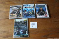 All 4 video game cases shown closed on wooden surface with lot number card visible.