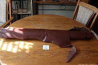 Full view of the brown leather hide spread out on wooden table showing front textured surface resembling alligator skin print.