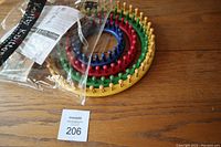 Set of 4 circular knitting looms stacked by size on a wooden surface, various colors yellow, green, red, blue with wooden pegs.