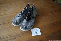Pair of Nike running shoes in grey and black on wooden surface with lot card