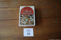 Box of Mille Bornes card game by Parker Brothers with vintage cover art, shown closed on wooden surface.