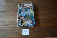 Front view of a stack of assorted comic books with X-Men cover comic on top, partially bagged.