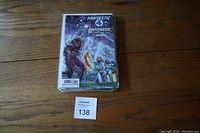 Top view of the comic book pile featuring a Fantastic Four comic on top, with a MaxSold lot number card 138 on a wood surface