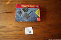 Photo of original Nuby Super Extendo box with product image and label on wooden surface.