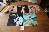Six Elvis Presley vinyl records including Elvis, Elvis Now, King Creole, Promised Land, Separate Ways, and one Dave Presley record laid out on table.