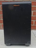Front view of the black Klipsch subwoofer showing scratches and scuffs on the surface.