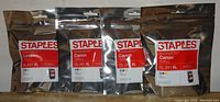 Four sealed Canon CL-241XL ink cartridges in foil packaging with Staples branding, showing front labels with color and branding.
