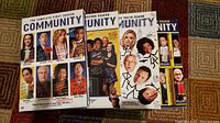 Four DVD cases arranged on carpeted floor showing seasons 1 through 4 of the Community TV series with character portraits on each cover.